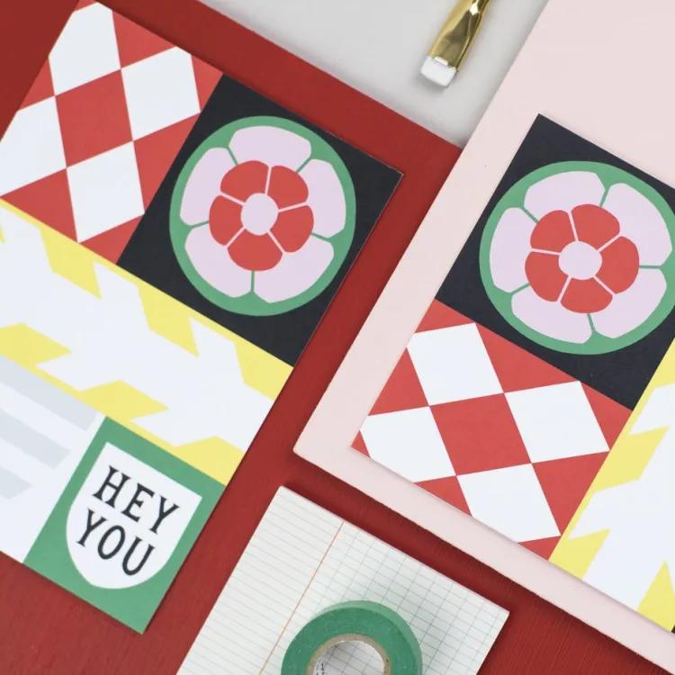 Greetings cards on pink and red background with paintbrush and tape