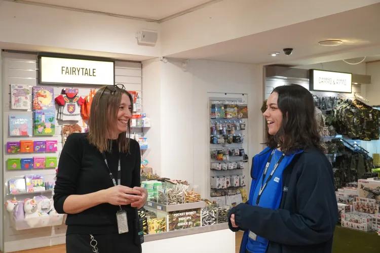 Two members of staff talking to each other with various toys in the background