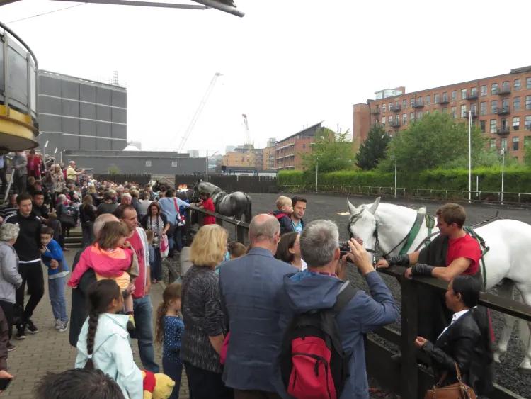 A crowd talk to a cavalry with his horse in a tiltyard