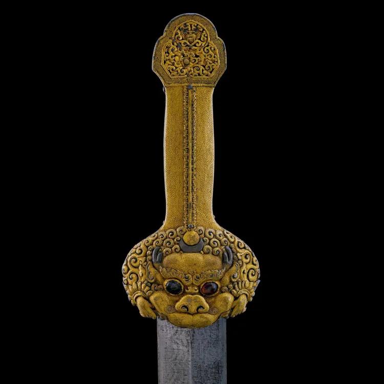 gold handle of a sword with a stylised lion face