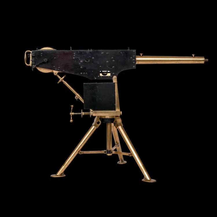 A brass tripod supports a rectangular black steel box with a brass barrel