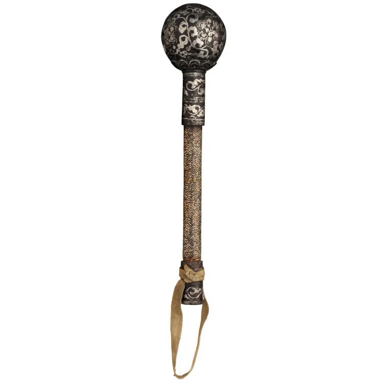 A metal ball with intricate silver engraving fixed a short wooden rod covered in shark or ray skin with a leather loop strap