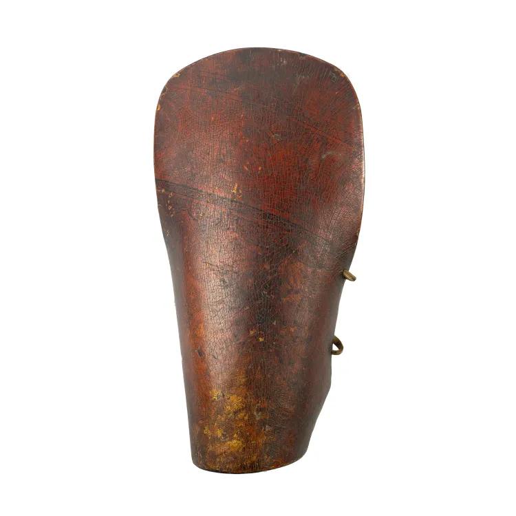 A leather bracer in brown with faint traces of red and yellow paint