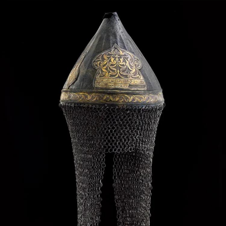 A metal cone-shaped helmet engraved with gold figures and suspending maille head and neck protection