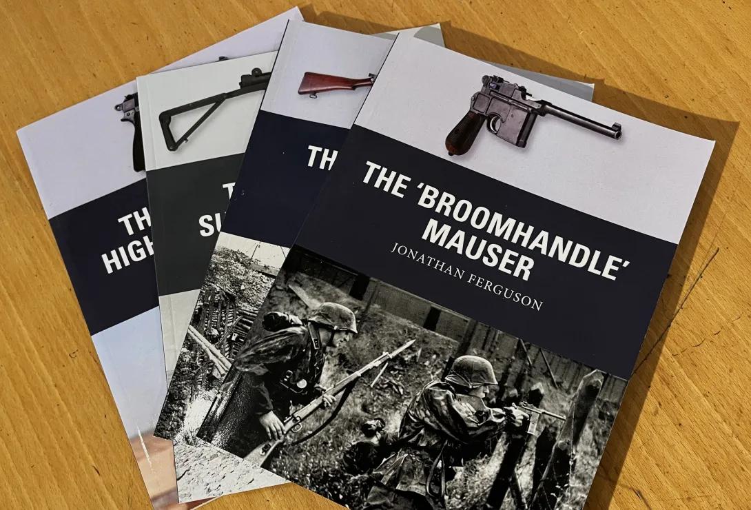 Four books published by Osprey fanned out on a table. The top book reads 'The Broomhandle Mauser'.